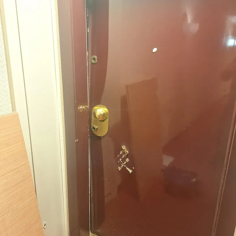 Bouton laiton et serrure sur porte bordeaux après effraction